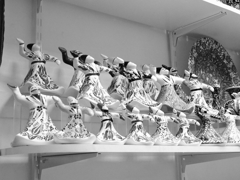 A row of ceramic figurines depicting dancers in traditional attire, arranged on a shelf.