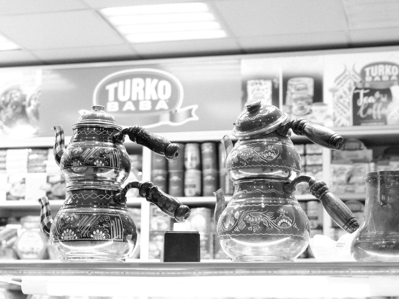 Two ornate Turkish coffee pots displayed on a shelf with colorful packaging in the background.