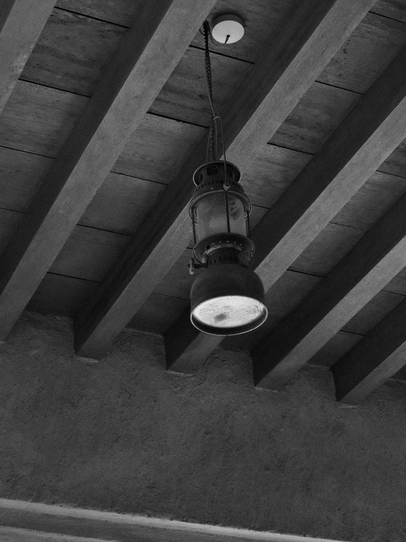 A vintage lantern hanging from a wooden ceiling with exposed beams.