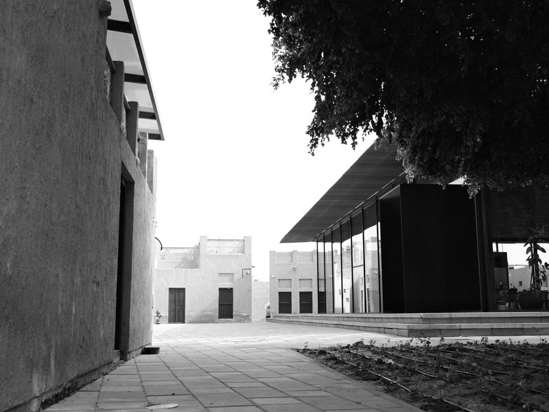 A minimalist architectural scene featuring a modern building and textured walls in black and white.