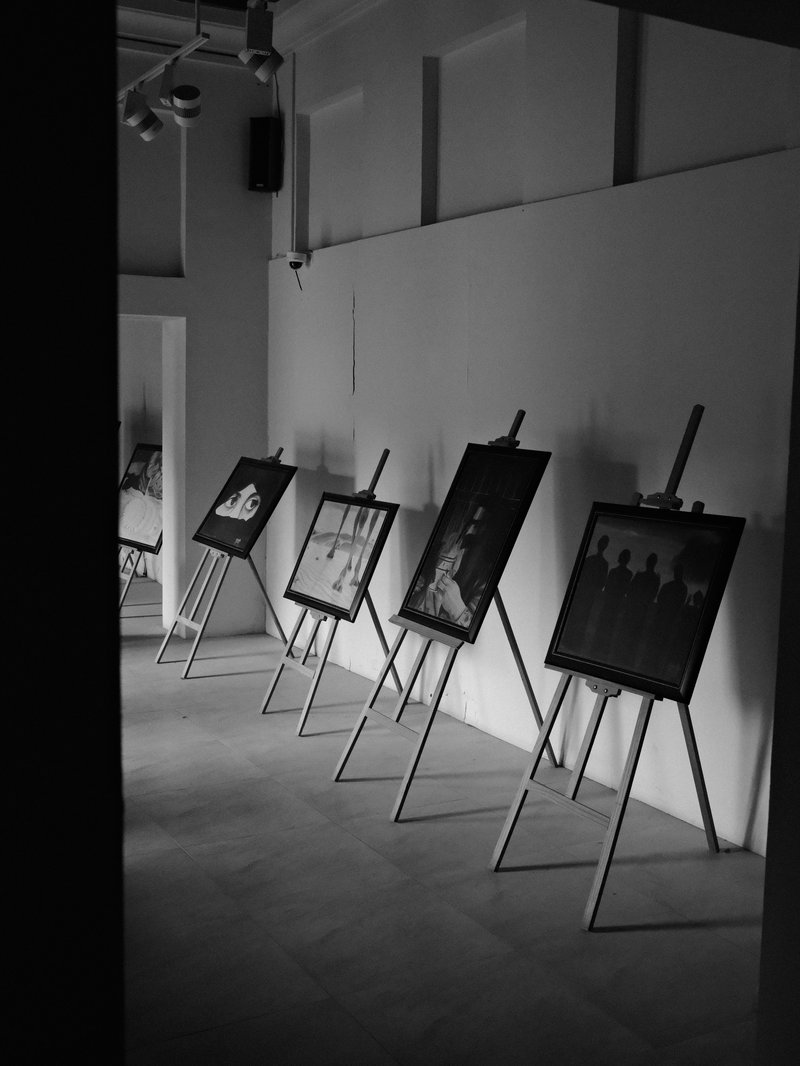 A gallery space with black and white photographs displayed on easels against a white wall.