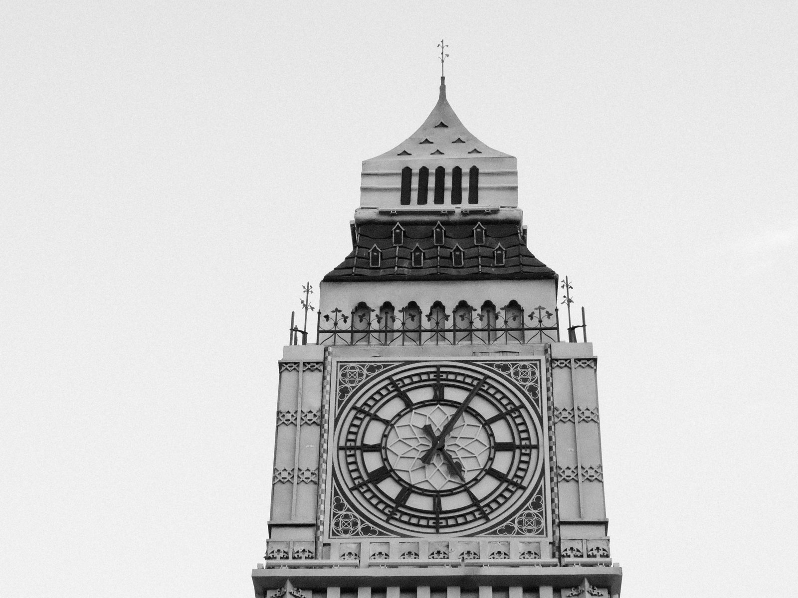Close-up view of a historic clock tower against a clear sky, showcasing intricate architectural details.