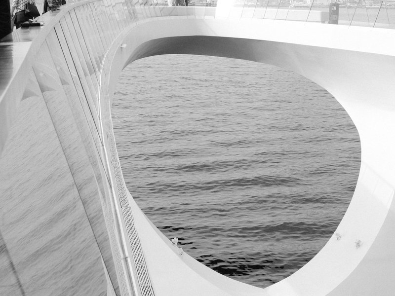 Abstract view of a modern bridge structure with water visible through an opening.