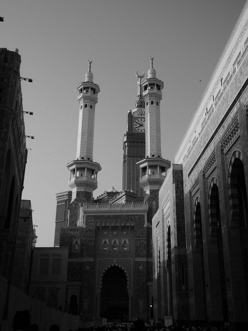 Black and white photo of a grand mosque with tall minarets and intricate architecture.