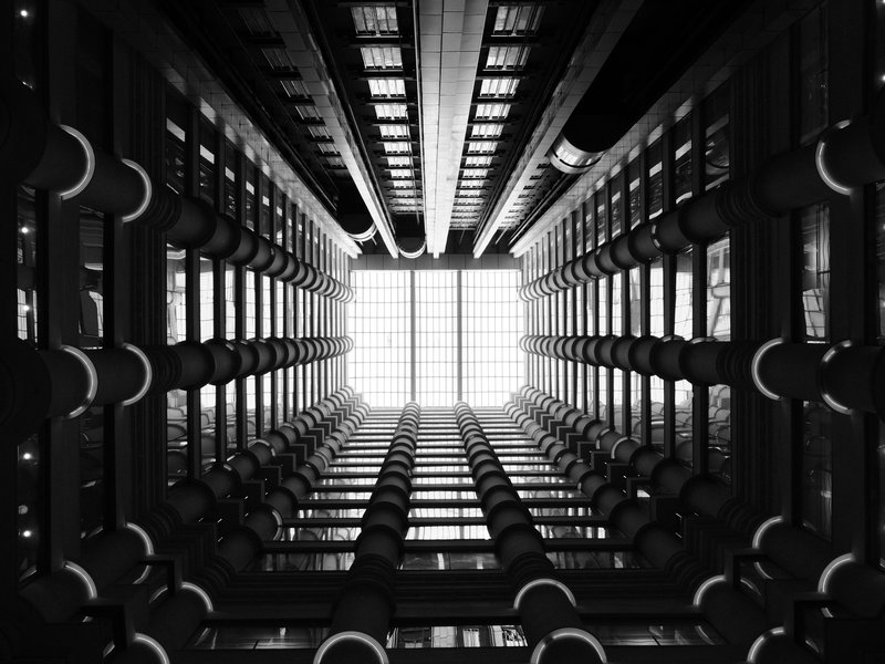 Looking up at a modern building's atrium with geometric lines and bright light from above.