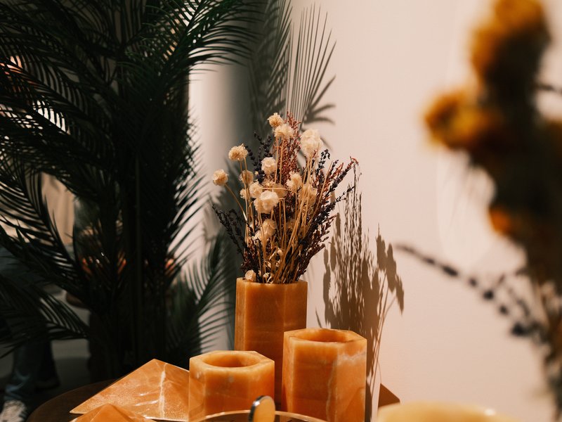 A cozy indoor scene featuring candles, dried flowers, and greenery on a wooden table.