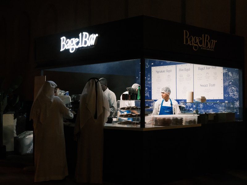 A food stall at night with staff serving customers in traditional attire.
