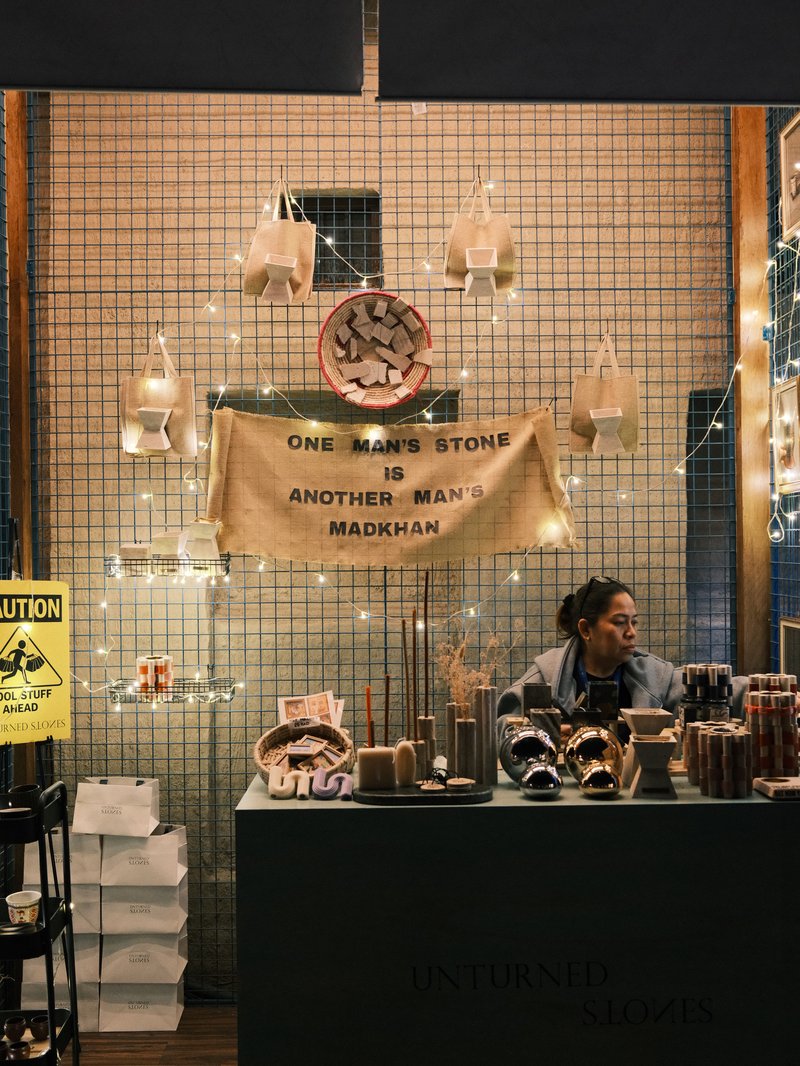 A cozy shop display featuring handmade goods and a woman behind the counter, illuminated by warm lights.