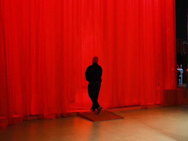 A person standing in front of a bright red curtain, creating a striking silhouette against the backdrop.
