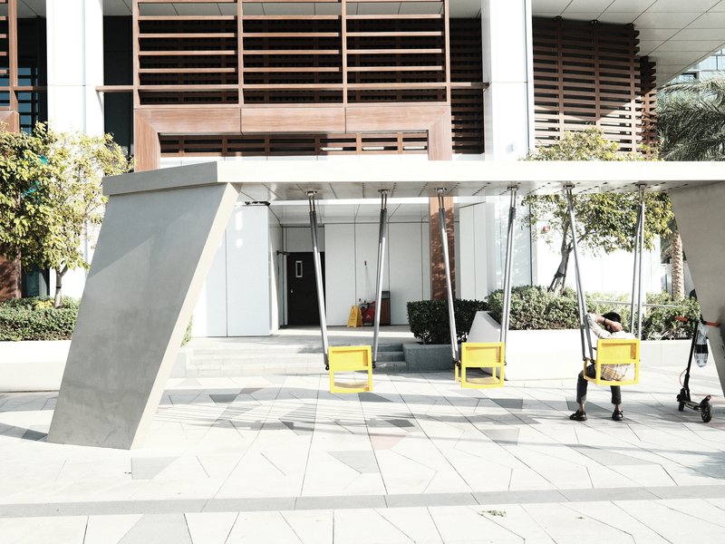 Modern outdoor seating area with yellow chairs under a sleek canopy in an urban setting.