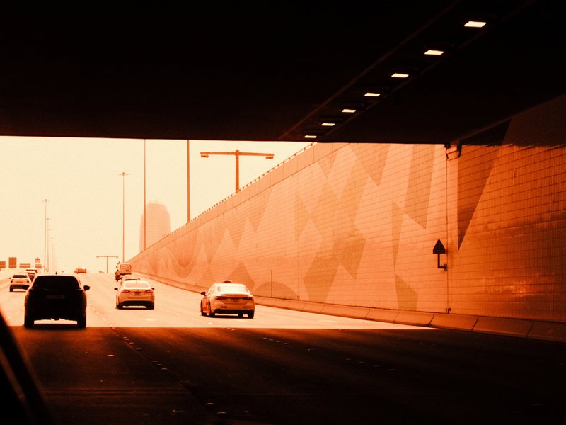 Cars driving through a tunnel with warm orange lighting and geometric wall patterns.