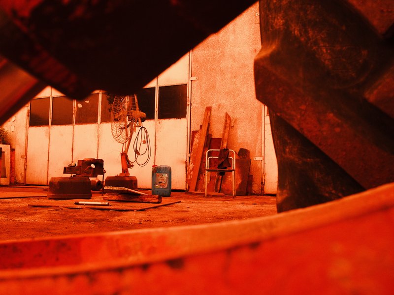 A dimly lit industrial scene with orange hues, featuring machinery and tools in a workshop.