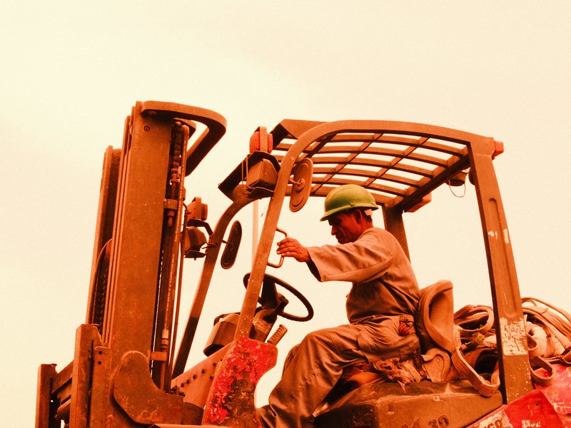 A construction worker operating a heavy machinery in an orange-tinted environment.