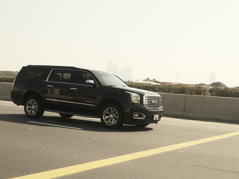 A black GMC SUV driving on a highway with a hazy background.