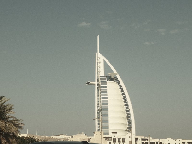 A tall, modern building with a unique sail-like design against a pale sky.