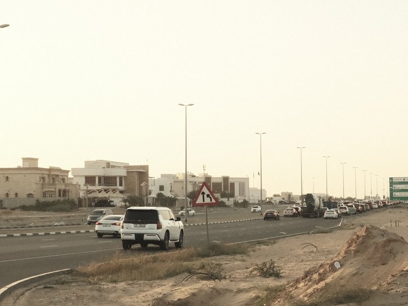 A busy road with vehicles and buildings in the background under a hazy sky.