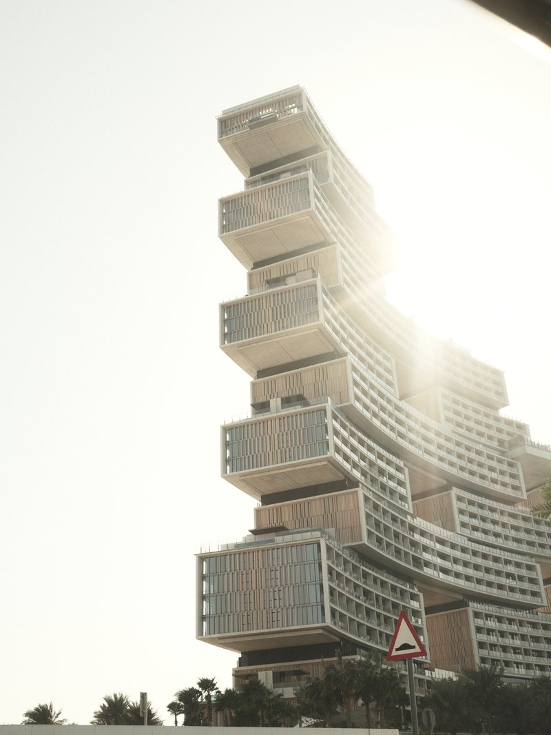 A modern architectural building with a unique stacked design, illuminated by sunlight.