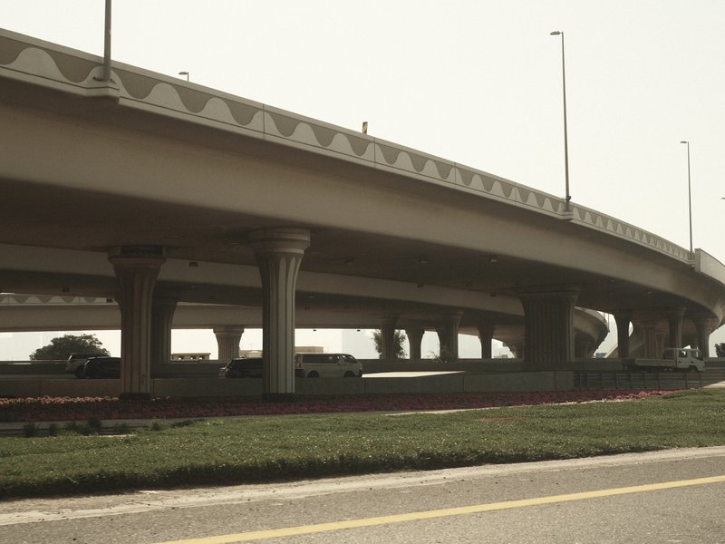 Low-angle view of a highway overpass with vehicles and green grass in the foreground.