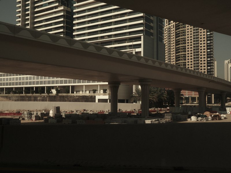 Urban scene featuring modern buildings and a highway overpass under a clear sky.