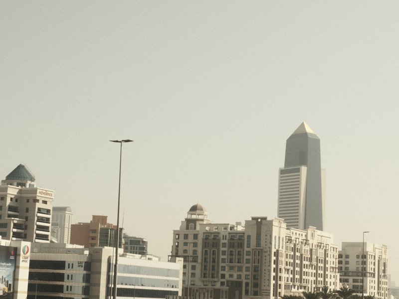 A skyline view featuring modern buildings under a hazy sky, with a prominent skyscraper in the background.