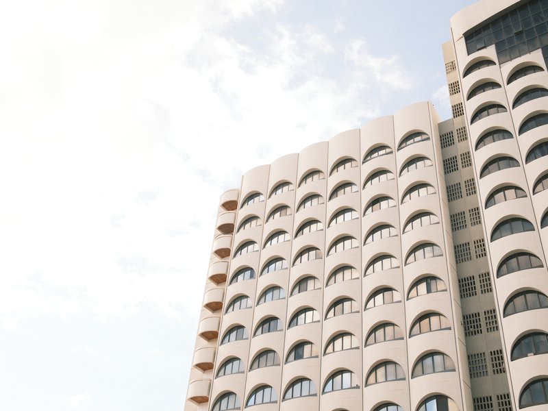 A modern building with curved architecture and multiple arched windows against a light sky.