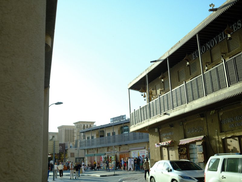 A bustling street scene with shops and pedestrians under a clear blue sky.