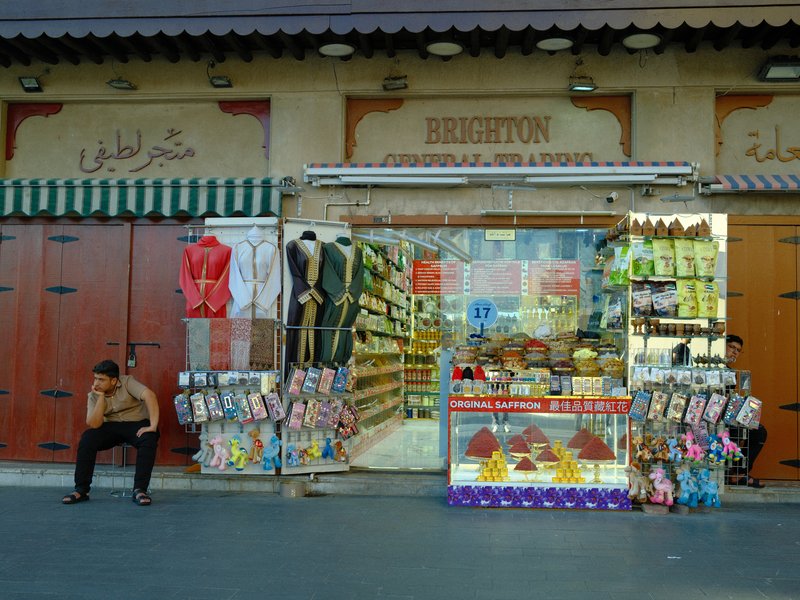 A vibrant street shop displaying colorful goods with a person sitting nearby.