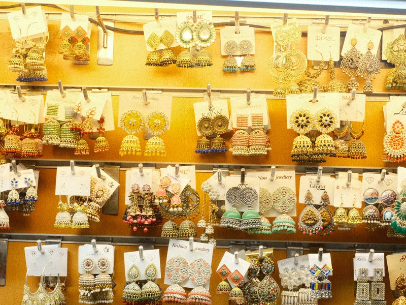 A colorful display of various earrings hanging on a wall with an orange background.