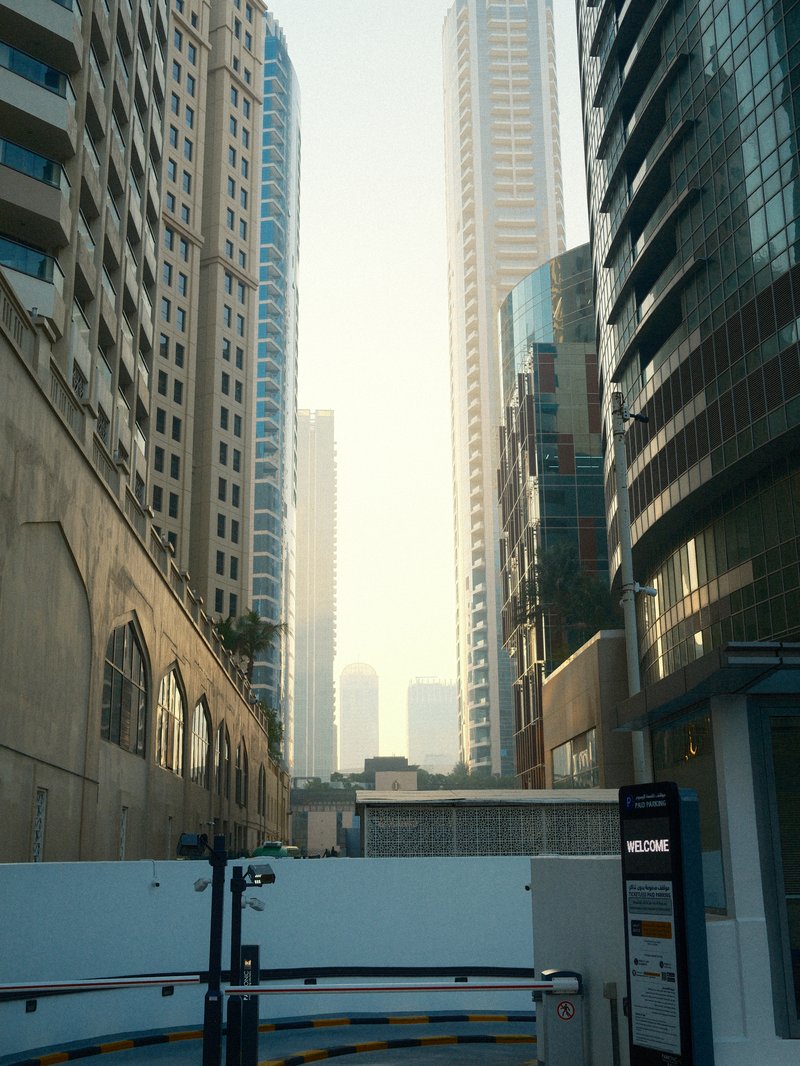 View of tall buildings in an urban setting with a hazy background and a construction barrier in the foreground.