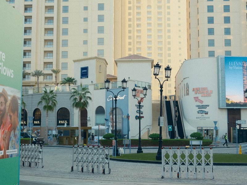 Urban scene featuring modern buildings, palm trees, and decorative street lamps.