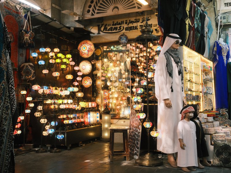 A vibrant market scene with colorful lanterns and traditional clothing on display.