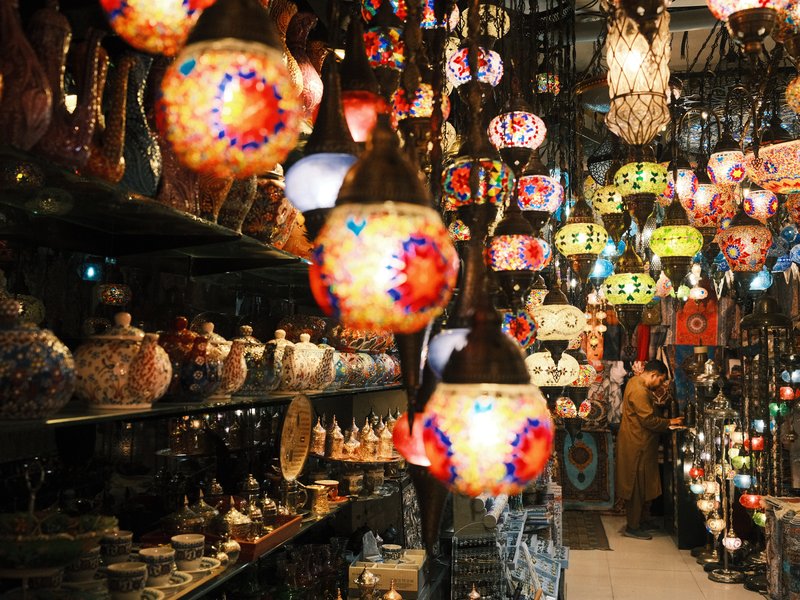 Colorful hanging lamps in a vibrant market filled with various decorative items.