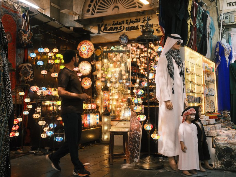 A bustling market scene with colorful lanterns and two figures, one adult and one child, in traditional attire.