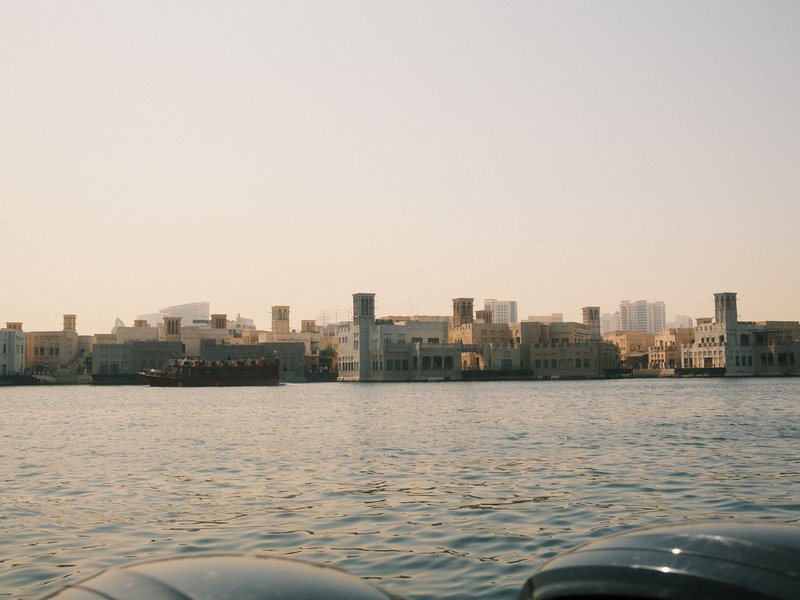 A view of a coastal city skyline with traditional architecture along the water's edge under a clear sky.