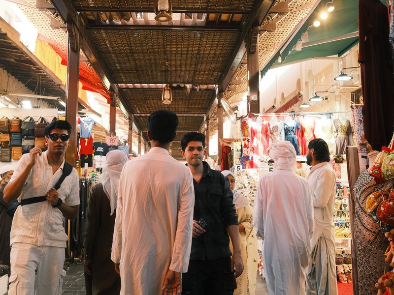 A bustling market scene with people interacting among colorful stalls and goods.