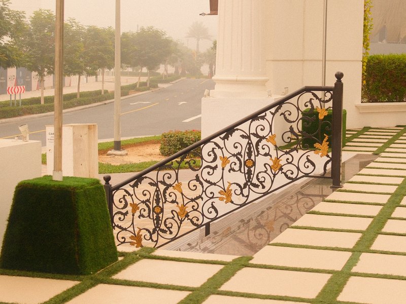 A decorative black iron railing beside a staircase leading to a foggy street.