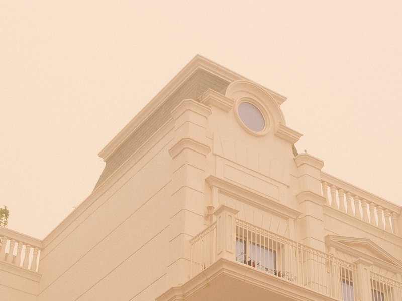 A pale building with a circular window under a hazy sky, creating a soft, muted atmosphere.