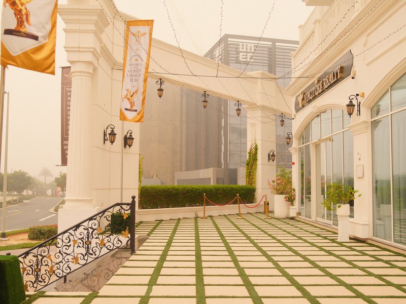 A foggy urban scene featuring a white building with decorative elements and a tiled pathway.