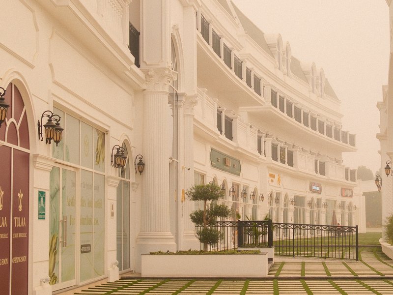 A foggy scene of a white building with curved architecture and green landscaping.