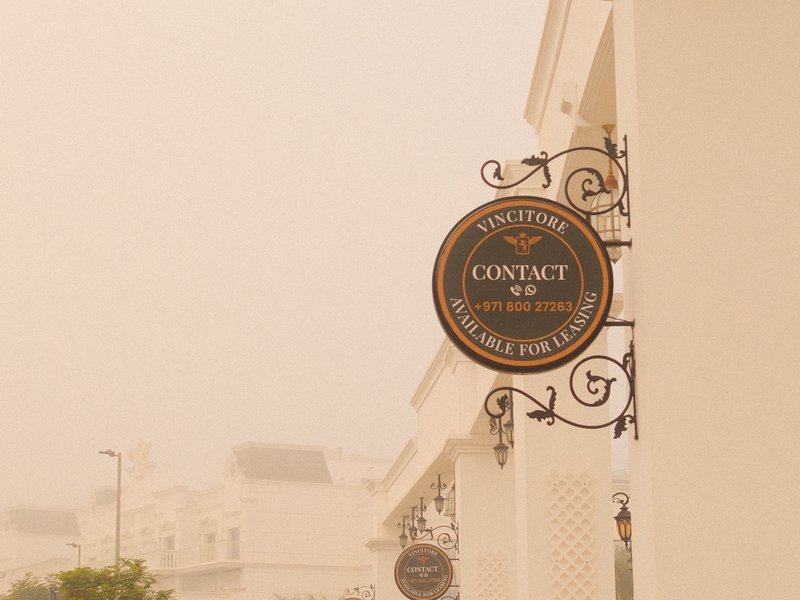 A vintage-style sign for a cafe, partially obscured by fog, with a soft, muted background.