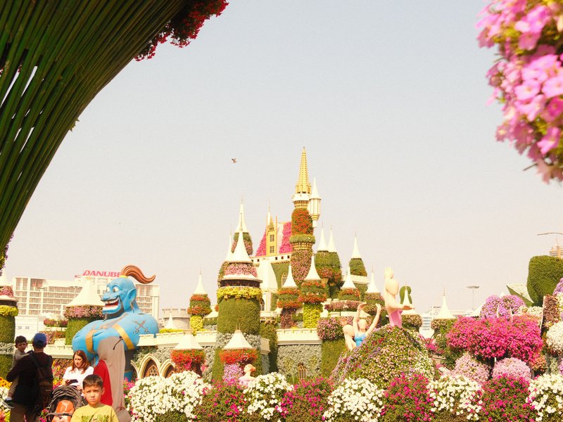 Colorful flower displays with a castle in the background, under a clear sky.