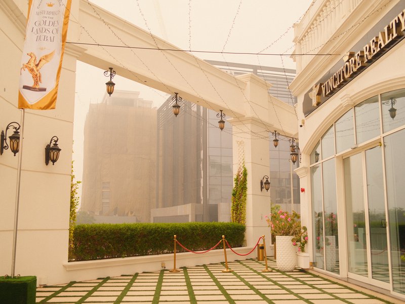 A misty outdoor terrace with modern architecture and hanging lights, surrounded by tall buildings.