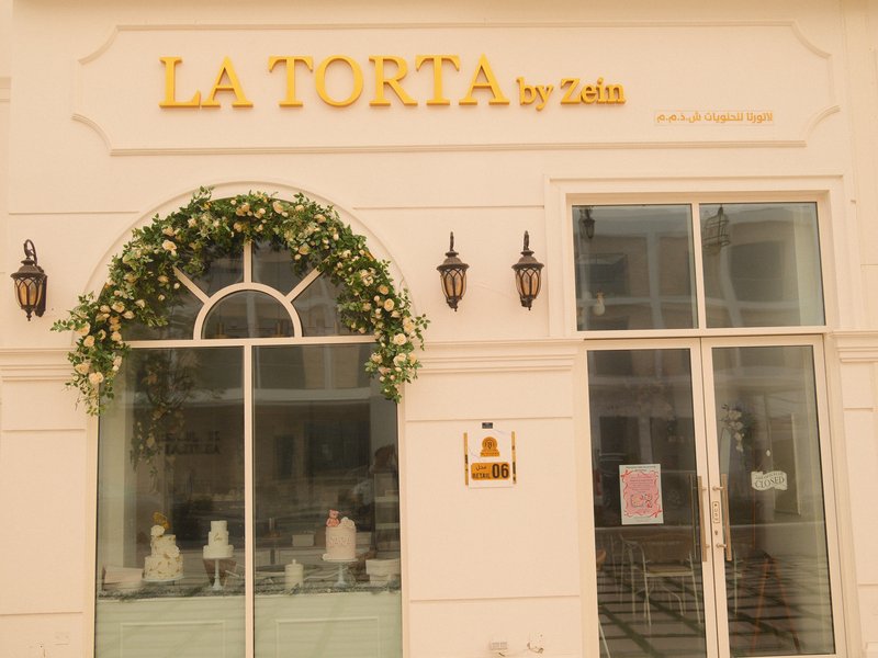 Exterior view of a bakery named 'La Tortia' with decorative plants and elegant signage.