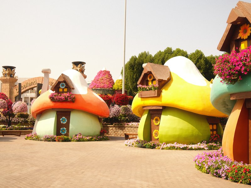 Colorful mushroom-shaped houses surrounded by flowers in a vibrant garden setting.