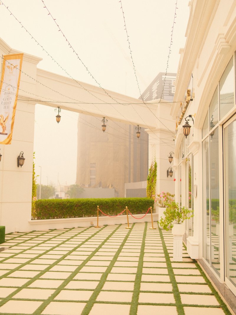 A serene outdoor patio with a patterned stone floor, surrounded by greenery and modern architecture.