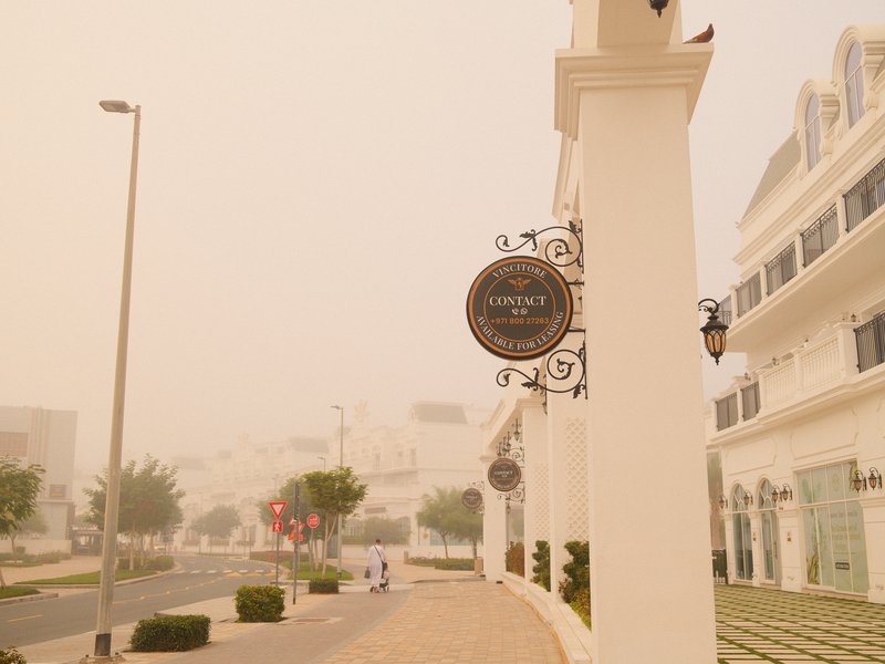 A street view with a sign in focus, surrounded by buildings and a hazy atmosphere.