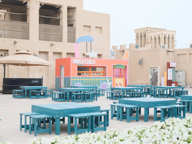 Colorful outdoor seating area with tables and a food stall in a historic urban setting.