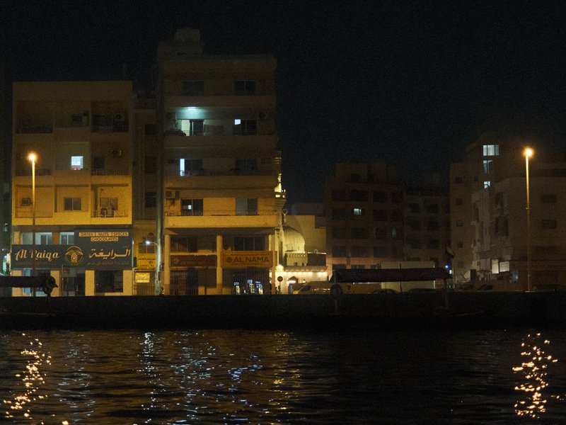 Nighttime urban scene with buildings and reflections on water.