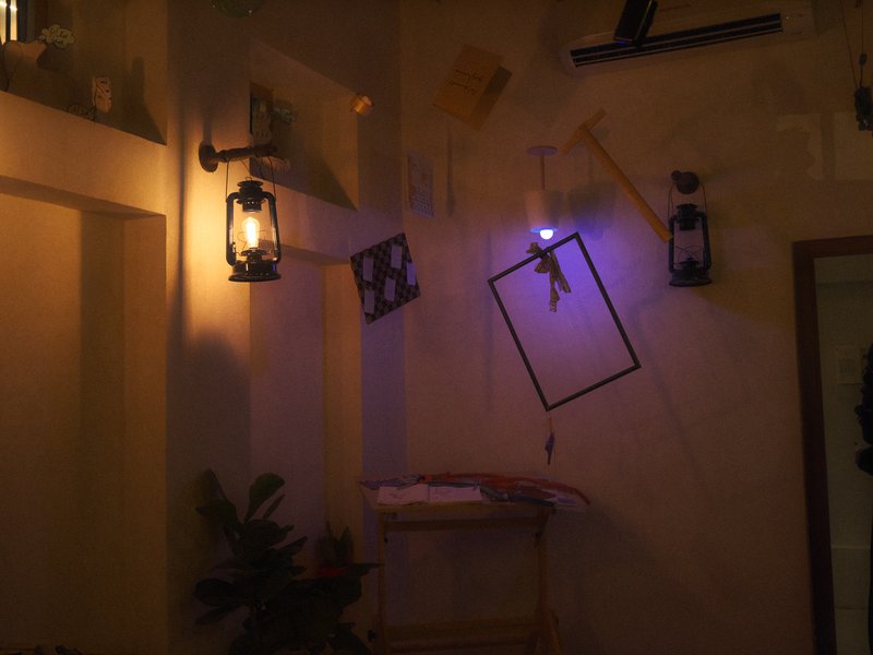 A cozy indoor scene with hanging lanterns and framed art against a textured wall.