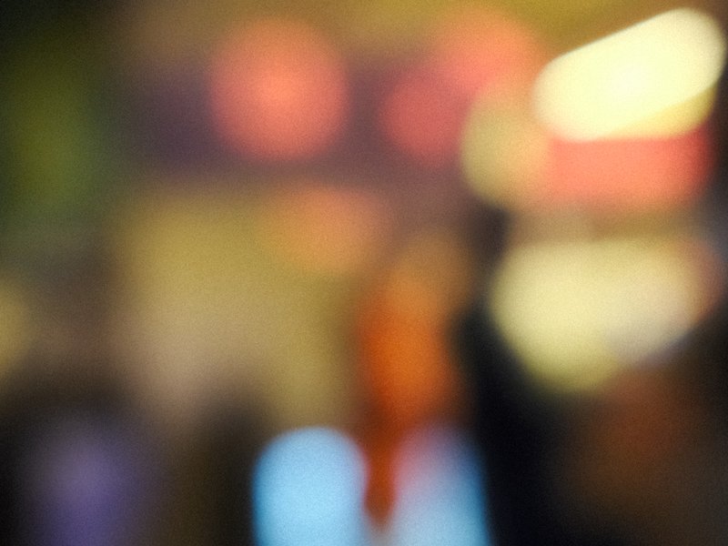 A blurred scene with indistinct shapes and colorful lights, creating an abstract atmosphere.
